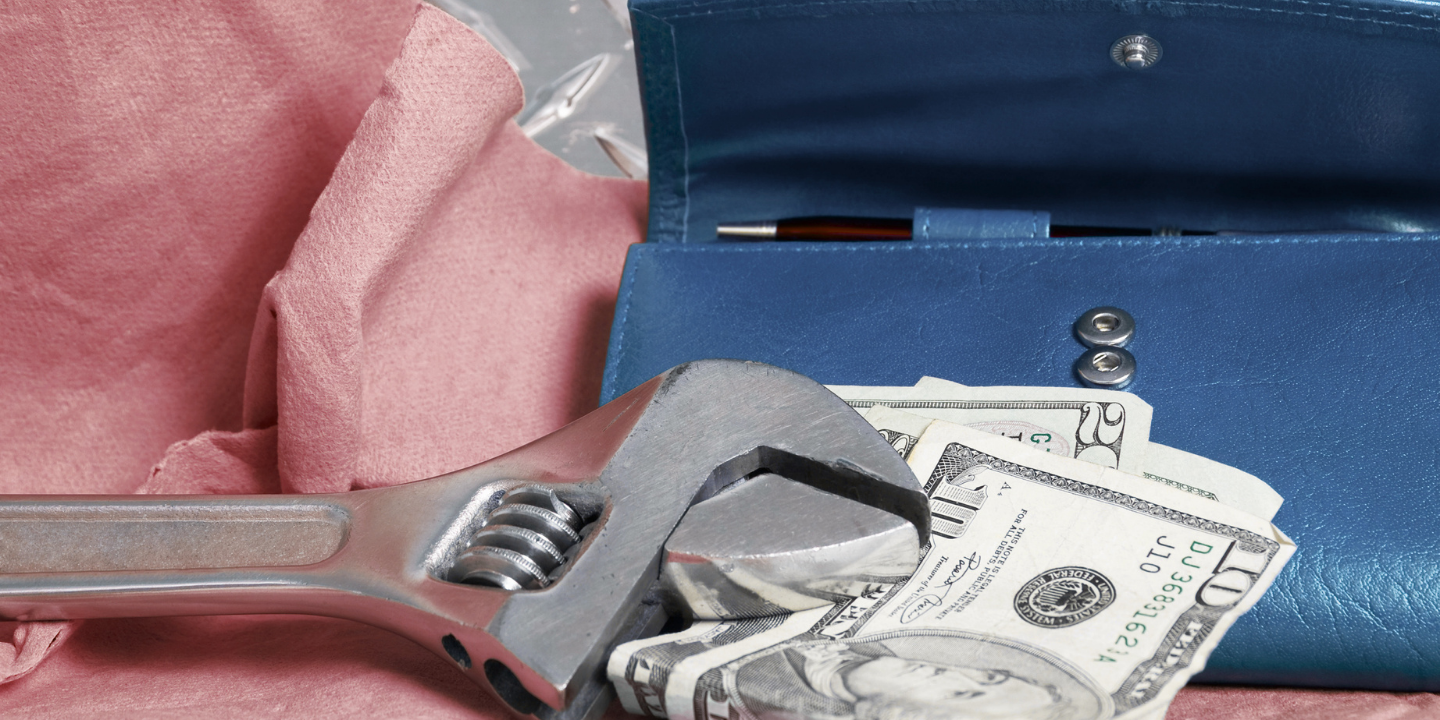 Crescent wrench on top of a stack of money.