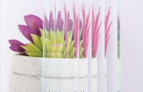 Reed Glass Sample Sample image of reed textured glass in front of succulent plant and vase.